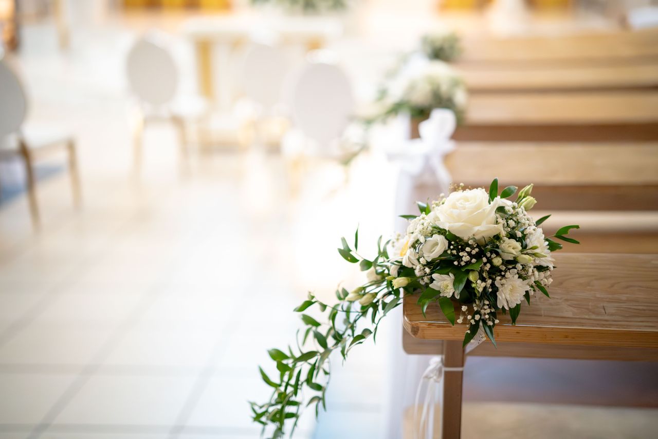 Beautiful floral arrangement on a wedding aisle with delicate white roses and greenery.